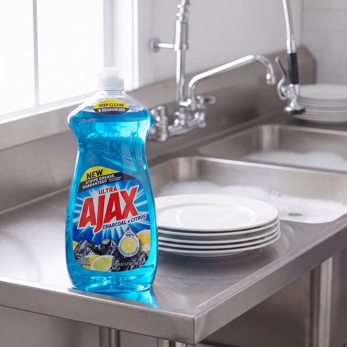 Ajax Charcoal and Citrus dish liquid 28 oz. bottle on the drainboard of a stainless steel commercial kitchen sink
