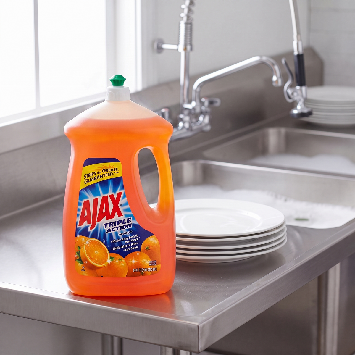 Ajax Ultra Triple Action Orange dish liquid 90 oz. bottle on the drainboard of a stainless steel commercial kitchen sink