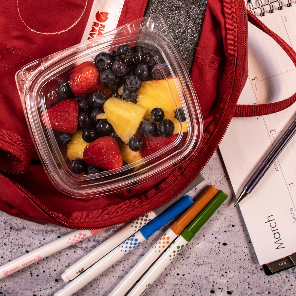 Dart CH12DED SafeSeal dome-lid container holding mixed fruit in a red backpack