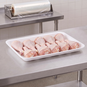 CKF 88151 #8DP white foam meat tray holding raw chicken drumsticks on a stainless steel table in a meat packing room