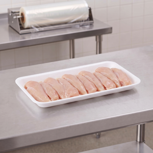 CKF 88168 #10S heavy duty white foam meat tray holding a row of raw chicken tenders on a stainless steel table in a meat packing room