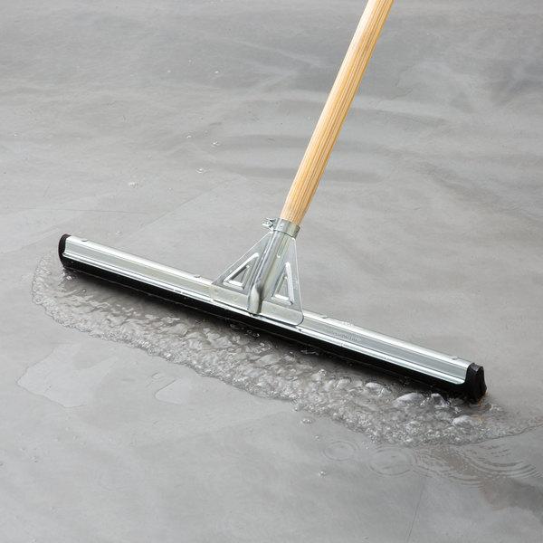 Commercial floor squeegee shown in use on a wet concrete floor, representative product image